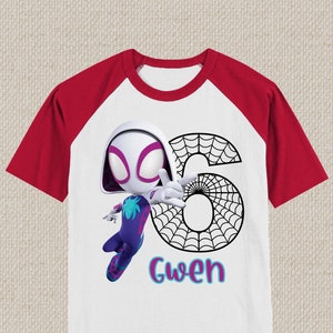 May include: White and red raglan t-shirt featuring a cartoon illustration of Spider-Gwen with the number 6 and the name "Gwen". The design includes a spider web and the character in a dynamic pose.