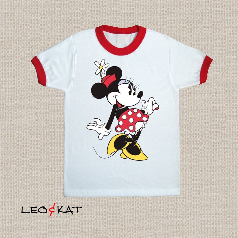 K&ouml;nnte beinhalten: Wei&szlig;es T-Shirt mit rotem Ringel und einem Motiv von Minnie Mouse, die einen roten Rock mit wei&szlig;en Punkten und eine rote Schleife tr&auml;gt. Das Motiv ist in Schwarzwei&szlig;.
