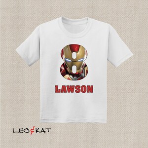 Pu&ograve; includere: Maglietta bianca con un designo di Iron Man rosso e oro a forma del numero 8. Il nome "LAWSON" &egrave; stampato sotto il design.
