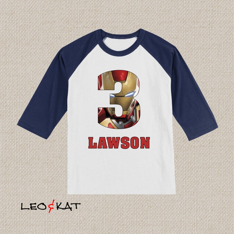 Pu&ograve; includere: Maglietta da baseball bianca e blu navy con un numero tre rosso con un'immagine di Iron Man. La maglietta ha il nome Lawson stampato sotto il numero.