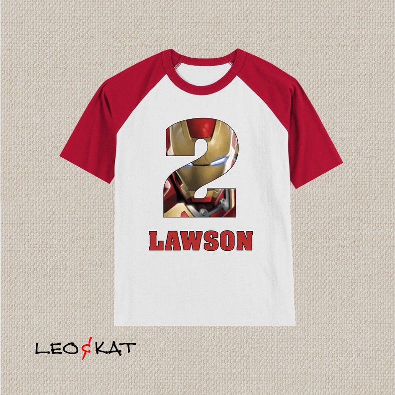 Pu&ograve; includere: Maglietta a maniche raglan bianca e rossa con un grande numero 2 che presenta un'immagine di Iron Man. La maglietta ha il nome "LAWSON" stampato sotto il numero.