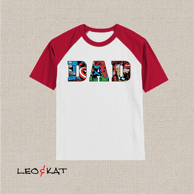 Op de afbeelding: Wit T-shirt met rode raglanmouwen met een afbeelding van het woord "DAD" gemaakt van afbeeldingen van Marvel-superhelden.