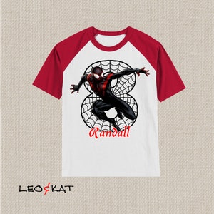 Puede incluir: Camiseta de manga raglan blanca y roja con un personaje de Spiderman negro y rojo en un dise&ntilde;o de telara&ntilde;a. El texto "Randall" est&aacute; impreso debajo del personaje.