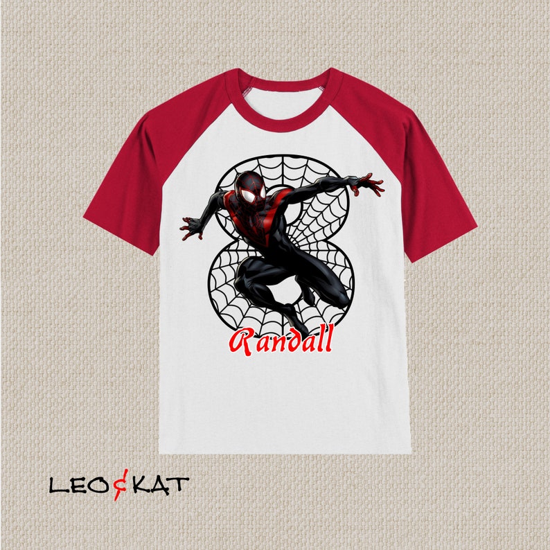Puede incluir: Camiseta de manga raglan blanca y roja con un personaje de Spiderman negro y rojo en un dise&ntilde;o de telara&ntilde;a. El texto "Randall" est&aacute; impreso debajo del personaje.