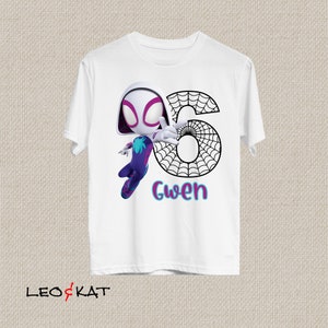 May include: White t-shirt with a cartoon Spider-Gwen graphic, a spiderweb-style number 6, and the name "Gwen" in blue and pink. This t-shirt is likely designed for a child's sixth birthday celebration.