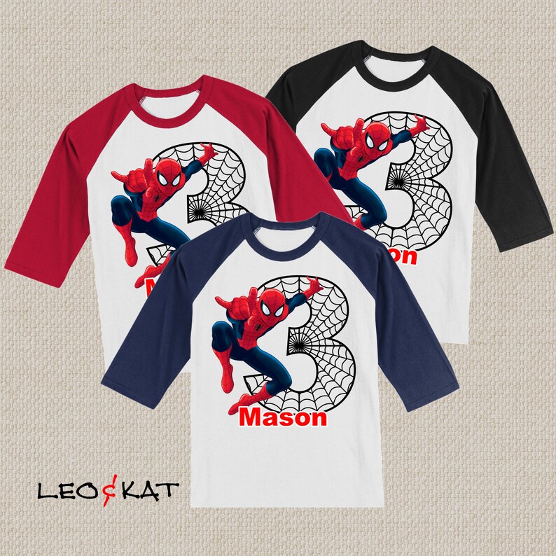 Puede incluir: Tres camisetas de estilo b&eacute;isbol con esquemas de colores rojo, blanco y azul. Las camisetas presentan un gr&aacute;fico de Spiderman con el n&uacute;mero 3 y el nombre "Mason" en una camiseta.