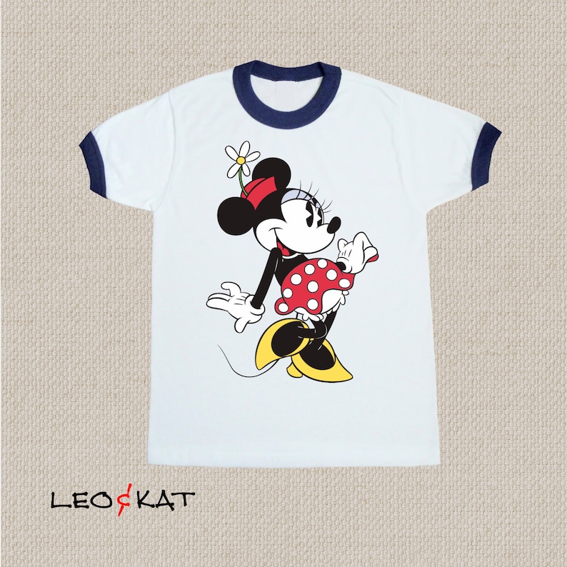 K&ouml;nnte beinhalten: Wei&szlig;es T-Shirt mit blauem Ringelkragen und einem Motiv von Minnie Maus, die einen roten Rock mit wei&szlig;en Punkten und eine rote Schleife tr&auml;gt.