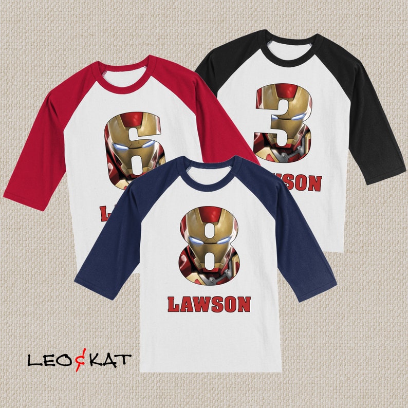 Pu&ograve; includere: Tre maglie da baseball con maniche rosse, nere e blu navy. Le maglie presentano un davanti bianco con un numero e il nome "Lawson" stampato sul davanti. I numeri sono 3, 6 e 8 e ogni numero &egrave; composto da un'immagine del viso di Iron Man.