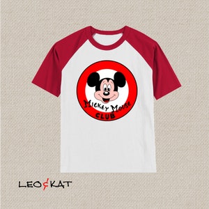 以下が含まれることがあります： 白と赤のラグランスリーブTシャツ。赤い円の中にミッキーマウスと「Mickey Mouse Club」の文字が描かれています。