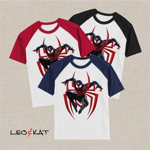 May include: Three different colour raglan t-shirts with a white base and a graphic of Miles Morales, Spider-Man, in a red and black suit, with a red spider web design behind him.