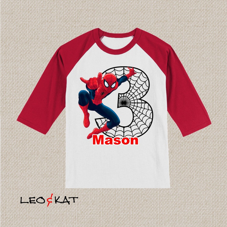 Puede incluir: Una camiseta de b&eacute;isbol blanca y roja con un gr&aacute;fico de Spiderman y el n&uacute;mero 3. La camiseta tiene el nombre "Mason" impreso en la parte delantera.