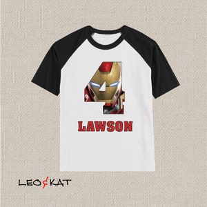 Pu&ograve; includere: Una maglietta da baseball bianca e nera con un numero quattro rosso che presenta il volto di Iron Man. Il nome Lawson &egrave; stampato in rosso sotto il numero.