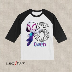 May include: A white and black raglan-style t-shirt with a cartoon Spider-Gwen illustration, the number 6, and the name "Gwen". The sleeves are black, and the body is white. The Spider-Gwen character is depicted in a dynamic pose, with a web design.
