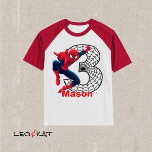 Puede incluir: Camiseta de manga raglan blanca y roja con un gr&aacute;fico de Spiderman y el n&uacute;mero 3. El gr&aacute;fico tambi&eacute;n incluye una telara&ntilde;a y el nombre "Mason".