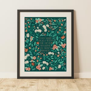 May include: Framed art print with a dark teal background and floral design. The print features the text "I can make deals with the devil because my dick's bigger" in a decorative font, surrounded by flowers.