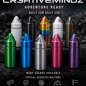 May include: A collection of ten cylindrical metal pill fobs with bullet-shaped caps and key rings, displayed in various colors including green, blue, silver, pink, purple, white, black, gold, and iridescent. Text reads CR3ATIVEMINDZ ADVENTURE READY.