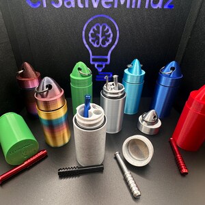 May include: A collection of cylindrical storage containers in various colors including rainbow, green, blue, silver, and red. Each container features a removable lid with a metal ring and holds small metal pipes in black, silver, and red.