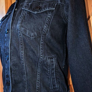 May include: A dark blue denim jacket with a button closure and multiple pockets.