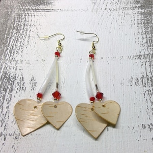 Può includere: Orecchini fatti a mano con ciondoli a forma di cuore in legno di betulla. Gli orecchini hanno ganci color oro, dettagli bianchi e perline di cristallo rosse. I cuori in legno di betulla presentano un motivo a venature naturali.