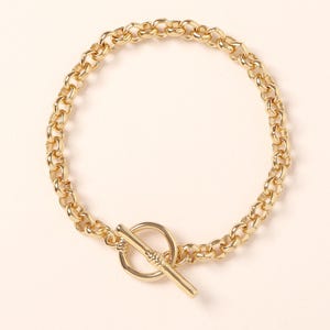 May include: A gold chain bracelet with a toggle clasp. The chain is made of thick, round links.