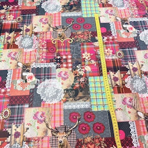 Könnte beinhalten: Ein Patchwork-Stoff mit Hirschkopfmotiven, Blumenmustern und Karomustern in Rot-, Rosa- und Grautönen. Der Stoff enthält Spitzendetails und ein gelbes Maßband, das eine Messung anzeigt. Das Design kombiniert rustikale und Vintage-Elemente.