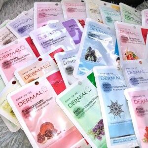 May include: A selection of face masks with various scents and ingredients, such as strawberry, lavender, milk, pomegranate, herb, white, rose, and hyaluronic acid. The masks are individually packaged in pouches with a white background and the word "DERMAL" printed in black.