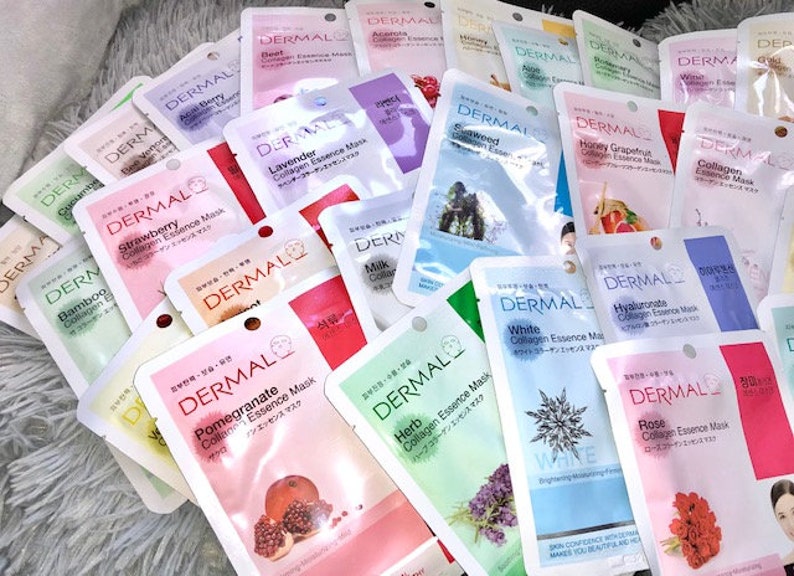 May include: A selection of face masks with various scents and ingredients, such as strawberry, lavender, milk, pomegranate, herb, white, rose, and hyaluronic acid. The masks are individually packaged in pouches with a white background and the word "DERMAL" printed in black.