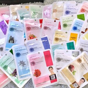 May include: A selection of face masks in individual packaging. The masks are white with colourful designs and text that reads "Dermal Essence Mask".