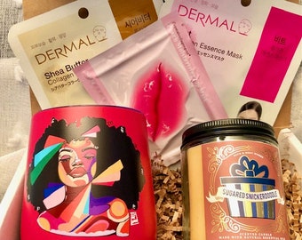 May include: A gift box filled with self-care items, including a red tumbler with a colourful abstract portrait of a woman, a pink lip-shaped face mask, a candle with a sugared snickerdoodle scent, and two sheet masks with Korean text.