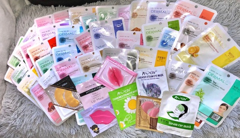 May include: A selection of face and eye masks in individual packets. The masks are in a range of colours and designs, including pink, blue, green and white. Some of the masks have text on them, such as "Dermal" and "Proctiv".