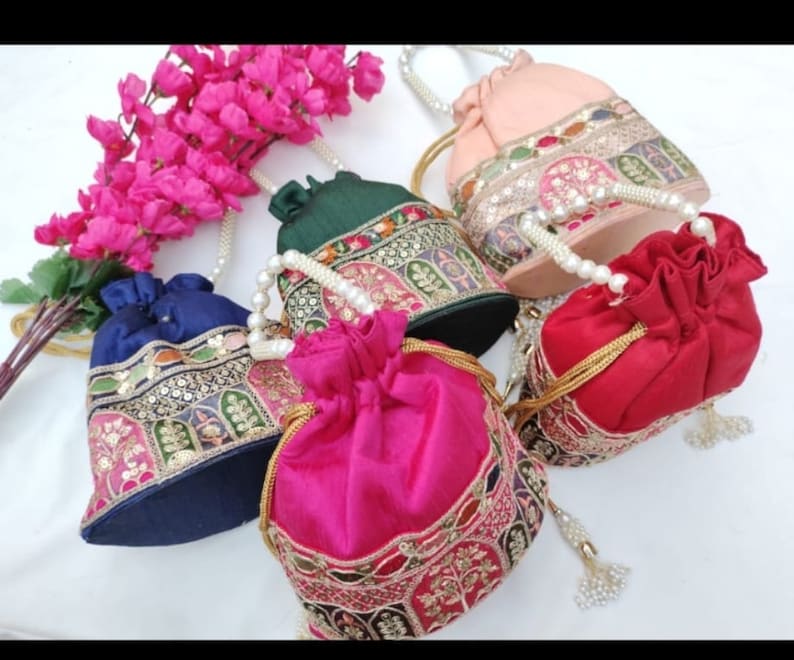 Puede incluir: Conjunto de cuatro bolsas de cord&oacute;n con asas de perlas. Las bolsas est&aacute;n hechas de seda y tienen dise&ntilde;os bordados en oro, verde, rosa y azul. Cada bolsa tiene un borla.