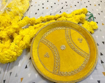 May include: A yellow velvet tray with gold trim and decorative embellishments. The tray is surrounded by yellow flower garlands.