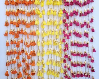May include: Three strands of decorative tassels with gold accents. The tassels are orange, yellow, and burgundy.
