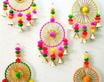 May include: Five colorful, circular wall hangings with a woven design, adorned with pom-poms and small bells. Each features a central pom-pom and a ring of radiating threads, with vibrant colors like pink, green, yellow, and orange.