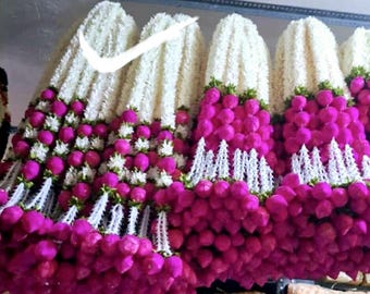May include: Several garlands of white and magenta flowers are displayed. The garlands are composed of white, fluffy flowers at the top, transitioning to magenta, spherical blooms. White, lace-like accents separate the layers of flowers.