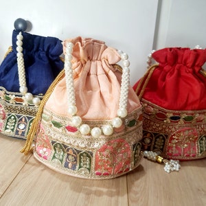 Puede incluir: Tres bolsas de cord&oacute;n con ribete de perlas y detalles bordados. Las bolsas son en tonos azul, melocot&oacute;n y rojo.