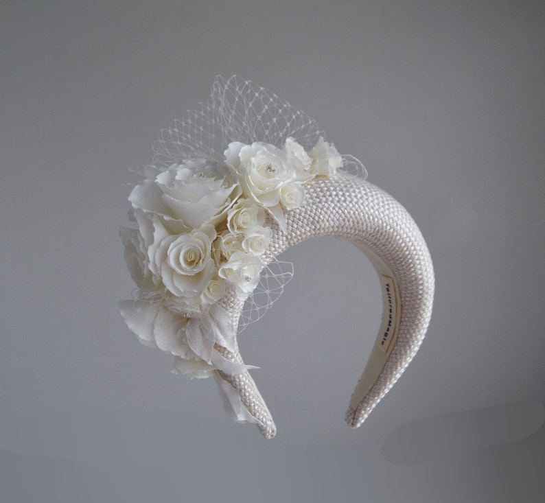 This fascinator for wedding guest  features a floral headpiece. Cream wedding fascinator headband with birdcage veil inspired by Kate Middleton headband hat. Perfect as elegant alternative to traditional wedding guest headband and veil hat for bride.