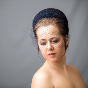 Navy fascinator headband for wedding guest with birdcage veil. Navy halo headband crown comes with velvet bow or without.
Navy hairband covered in sequins tweed. Wedding fascinator trimmed with bow on the right side of the navy blue padded headband.