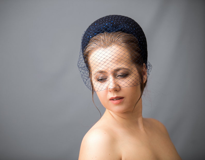 Navy fascinator headband for wedding guest with birdcage veil. Navy halo headband crown comes with velvet bow or without.
Navy hairband covered in sequins tweed. Wedding fascinator trimmed with bow on the right side of the navy blue padded headband.