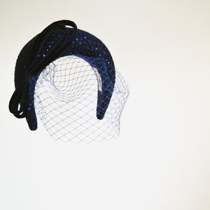 Navy fascinator headband for wedding guest with birdcage veil. Navy halo headband crown comes with velvet bow or without.
Navy hairband covered in sequins tweed. Wedding fascinator trimmed with bow on the right side of the navy blue padded headband.