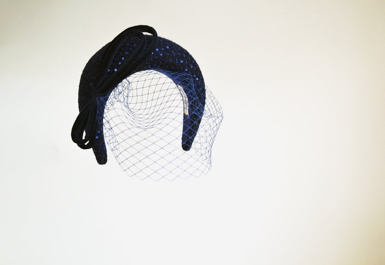 Navy fascinator headband for wedding guest with birdcage veil. Navy halo headband crown comes with velvet bow or without.
Navy hairband covered in sequins tweed. Wedding fascinator trimmed with bow on the right side of the navy blue padded headband.