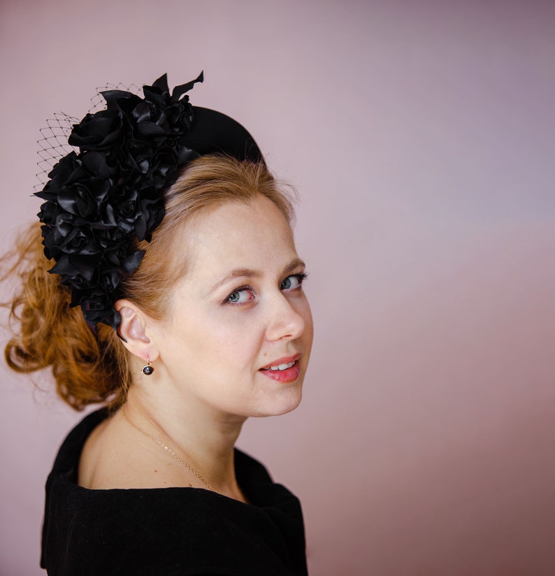 Black fascinator headband for wedding guest is hand made. Black flower crown inspired by Kate Middleton. Padded halo headband comes with birdcage veil or whithout. Beads can be added to the halo headpiece.
Wedding guest hairband trimmed with flowers.