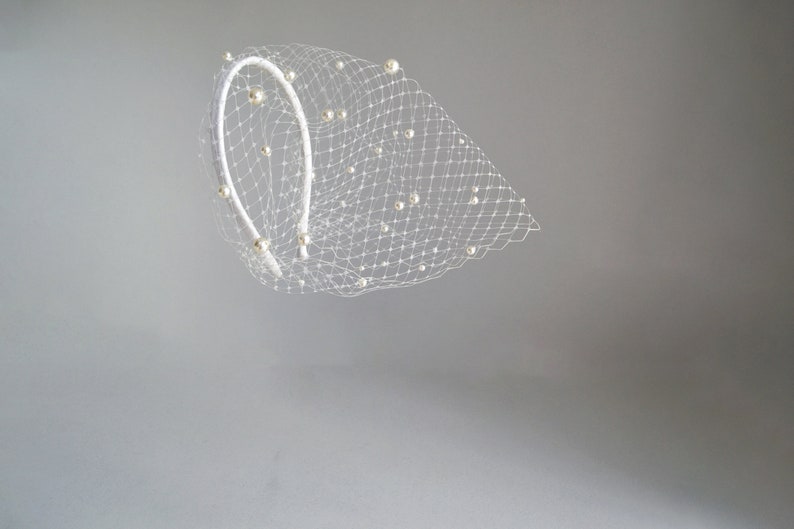 Wedding birdcage blusher veil features with velvet headband and faux pearls. Bridal hairband with pearl bandeau veil is hand made. Bachelorette veil come with a scattering of pearls or without.
Fascinator headband has been covered with bird cage veil