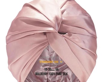 Op de afbeelding: Een roze satijnen turban met de tekst "OLKONFO STANDARD 100", "Getest op schadelijke stoffen", "www.oko-tex.com/standard100", "16-30 MOMME 6A" en "MULBERRY 100% PURE SILK".