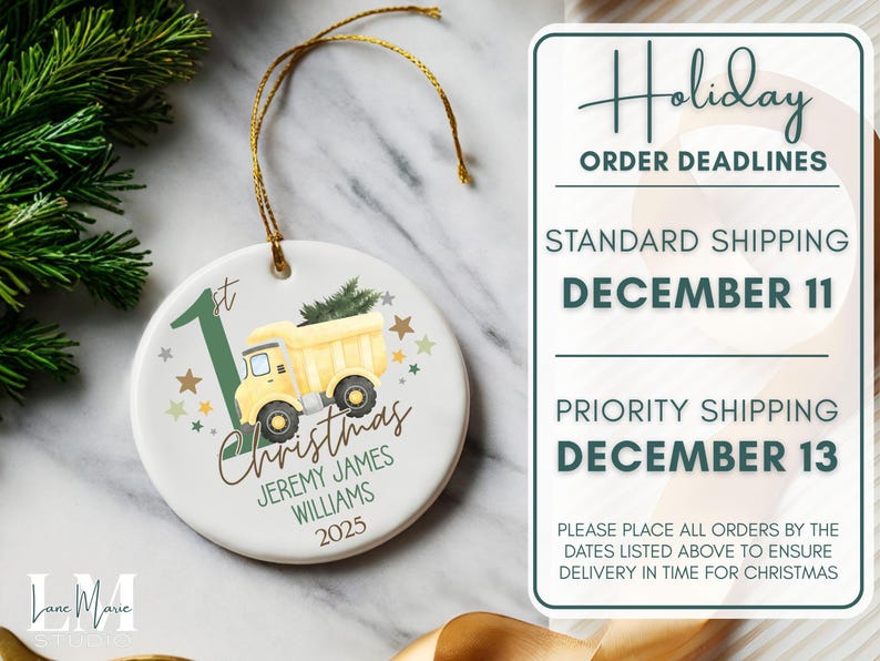 May include: A white ceramic Christmas ornament with a yellow dump truck carrying a Christmas tree. The ornament has the text "1st Christmas" and a name and year. A gold string is attached for hanging.