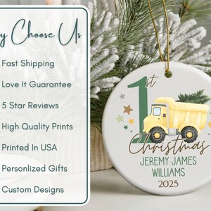 May include: A white ceramic Christmas ornament featuring a yellow dump truck carrying a green Christmas tree. The ornament has the text "1st Christmas" and personalized details. The ornament is hanging with a gold string.