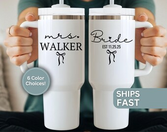May include: Two white insulated tumblers with handles. One tumbler reads "mrs. WALKER" with a bow graphic, the other reads "Bride EST 11.25.25" with a bow graphic. The image also includes a graphic that says "6 Color Choices!"