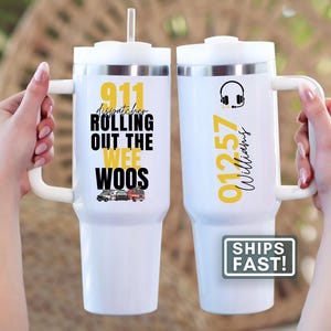 May include: Two white stainless steel tumblers with handles and lids. One features the text 911 dispatcher ROLLING OUT THE WEE WOOS with emergency vehicle graphics. The other displays a headset icon, the number 01257, and the name Williams in black and yellow.