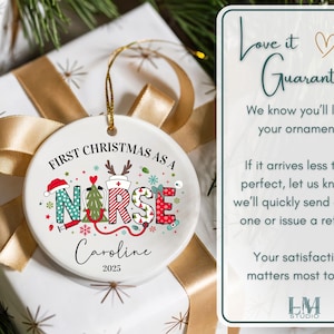 May include: A round Christmas ornament with the text "First Christmas as a Nurse" and the name "Caroline" below. The ornament has a gold string for hanging and is decorated with festive nurse-themed graphics. The ornament is on a wrapped gift.