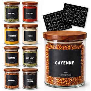 May include: A selection of glass spice jars with wooden lids, each labelled with a black sticker. Spices include parsley, paprika, turmeric, onion, mustard, bay leaf, cayenne, and black pepper. Also included are black label stickers with various spice names.